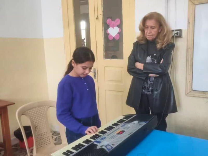 A young girl (Besan) concentrates while playing an electronic keyboard at the Little Dreams Center in Banyias, Syria.