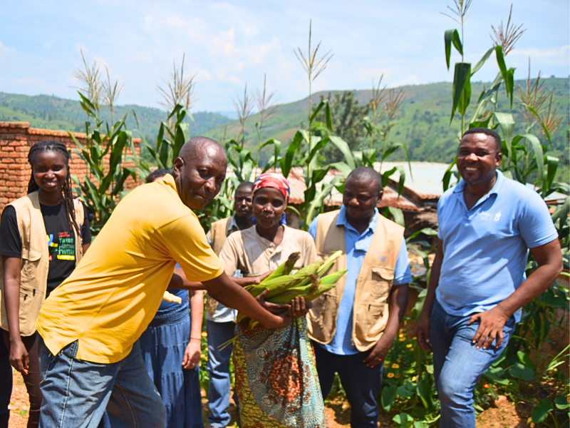 Una donna in Burundi mostra grandi pannocchie di mais raccolte grazie all'uso del fertilizzante naturale prodotto dalle latrine ecologiche.