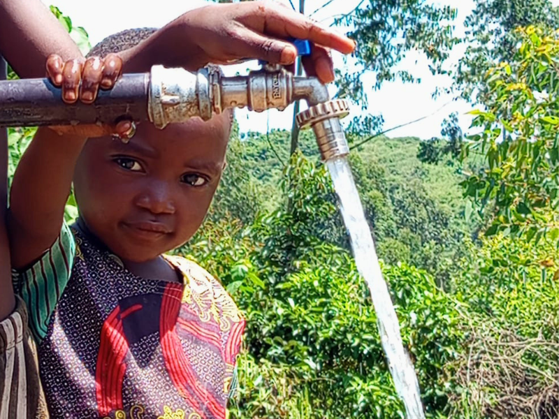 Una bambina accanto a una delle 19 fontanelle pubbliche riabilitate mentre scorre l'acqua pulita.