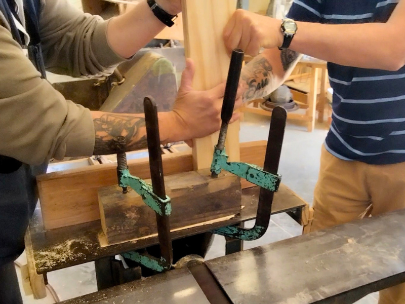 Mani di un detenuto al lavoro nel laboratorio di falegnameria per il progetto di reinserimento sociale.