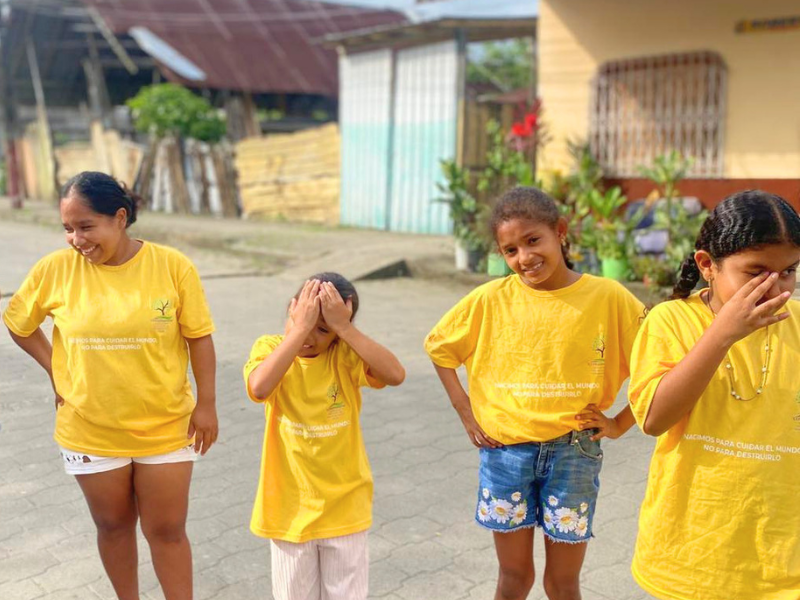 Quattro giovani partecipanti del Progetto Sunrise in Ecuador posano sorridenti con le magliette gialle dei Club Ecologici.