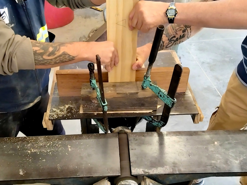 A close-up of the hands of two inmates working with wood in the carpentry workshop of the Ripartire project for social reintegration in prisons in Uruguay.