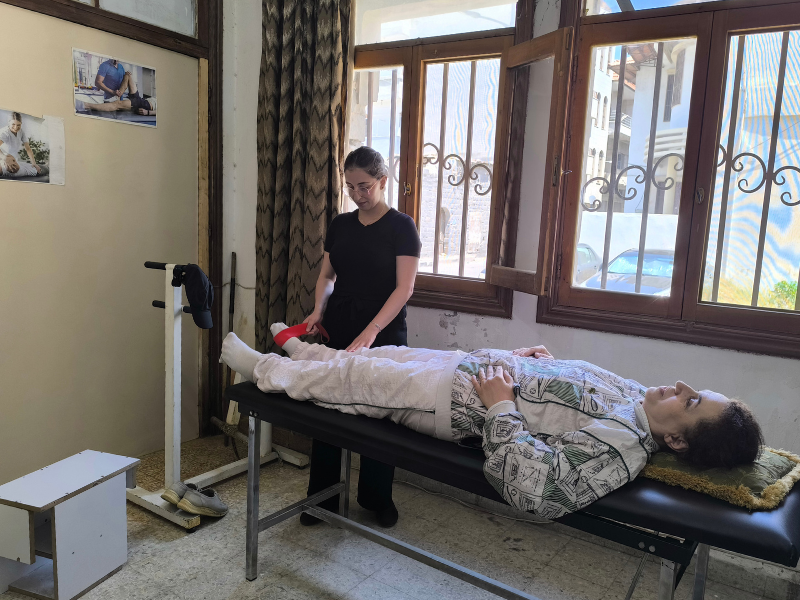 La terapista Ola assiste la signora Sahar durante gli esercizi di riabilitazione della schiena, all'interno del centro per i progetti umanitari in Siria.