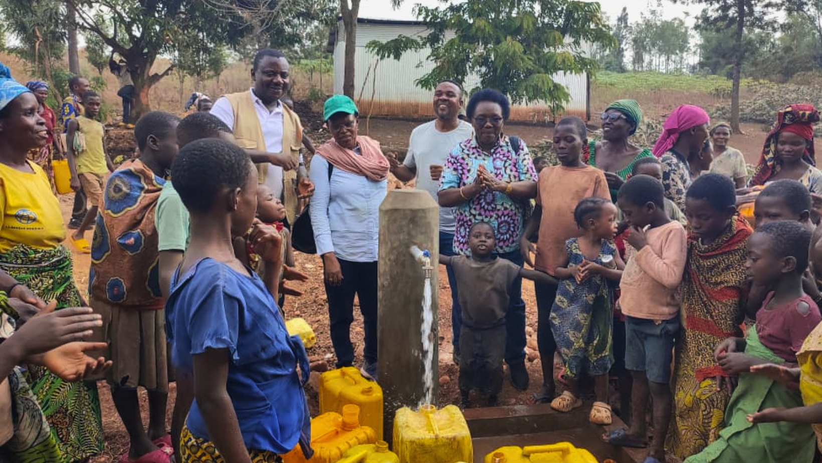 Una folla di abitanti del villaggio di Gicaca, in Burundi, si raduna attorno a una nuova fontanella pubblica. Un bambino in primo piano si erge con le braccia spalancate, mentre l'acqua limpida e potabile sgorga per la prima volta. Altri uomini e donne guardano l'acqua quasi con rispetto