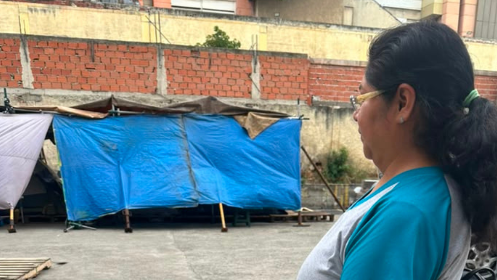 Donna che osserva baracche e rifugi improvvisati in un cortile urbano in Venezuela.