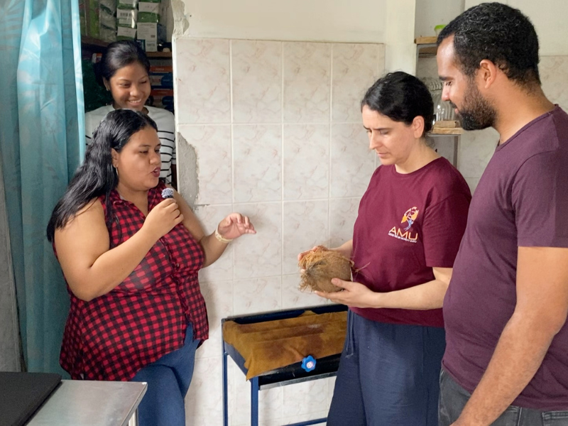 Lia dell'AMU osserva una noce di cocco durante la spiegazione del processo artigianale nel laboratorio della microimpresa COCO&SOL, sostenuta dal Progetto Sunrise+ Ecuador.