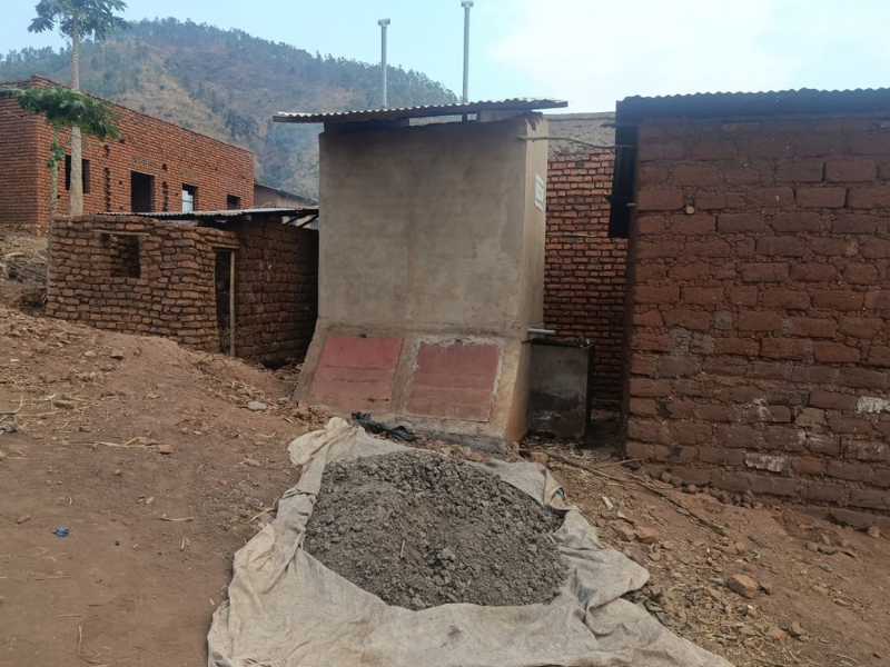 Nuova latrina ecologica in muratura con tubi di ventilazione e cumulo di compost organico pronto all'uso in Burundi.