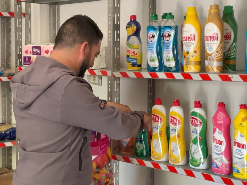 Tony Jarouj ordina i flaconi di detersivo sugli scaffali della sua bottega in Siria, aperta grazie a RestarT