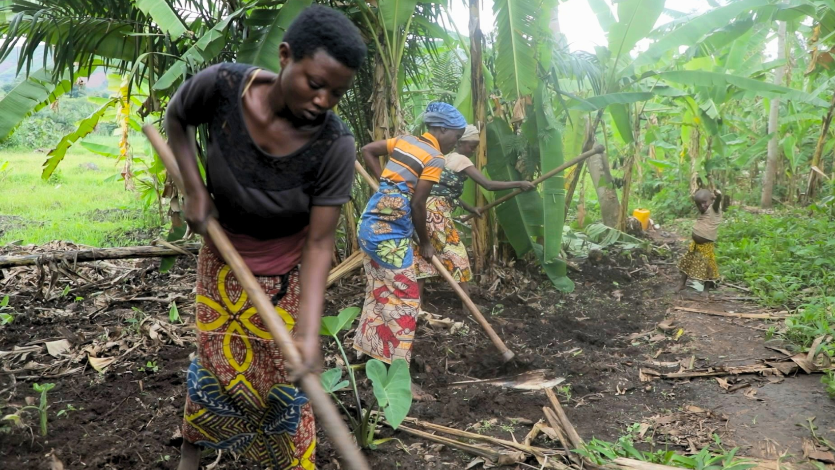 Tre donne sono al lavoro, in Burundi, per scavare le trincee per il nuovo acquedotto, Indossano abiti colorati e imbracciano le pale nell'atto di scavare