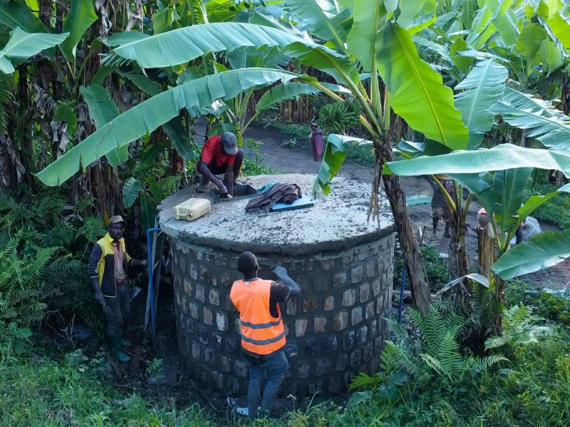 Un gruppo di uomini in Burundi lavora attorno a un grande serbatoio d'acqua costruito in muratura